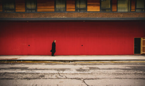 A man walking along a red wall